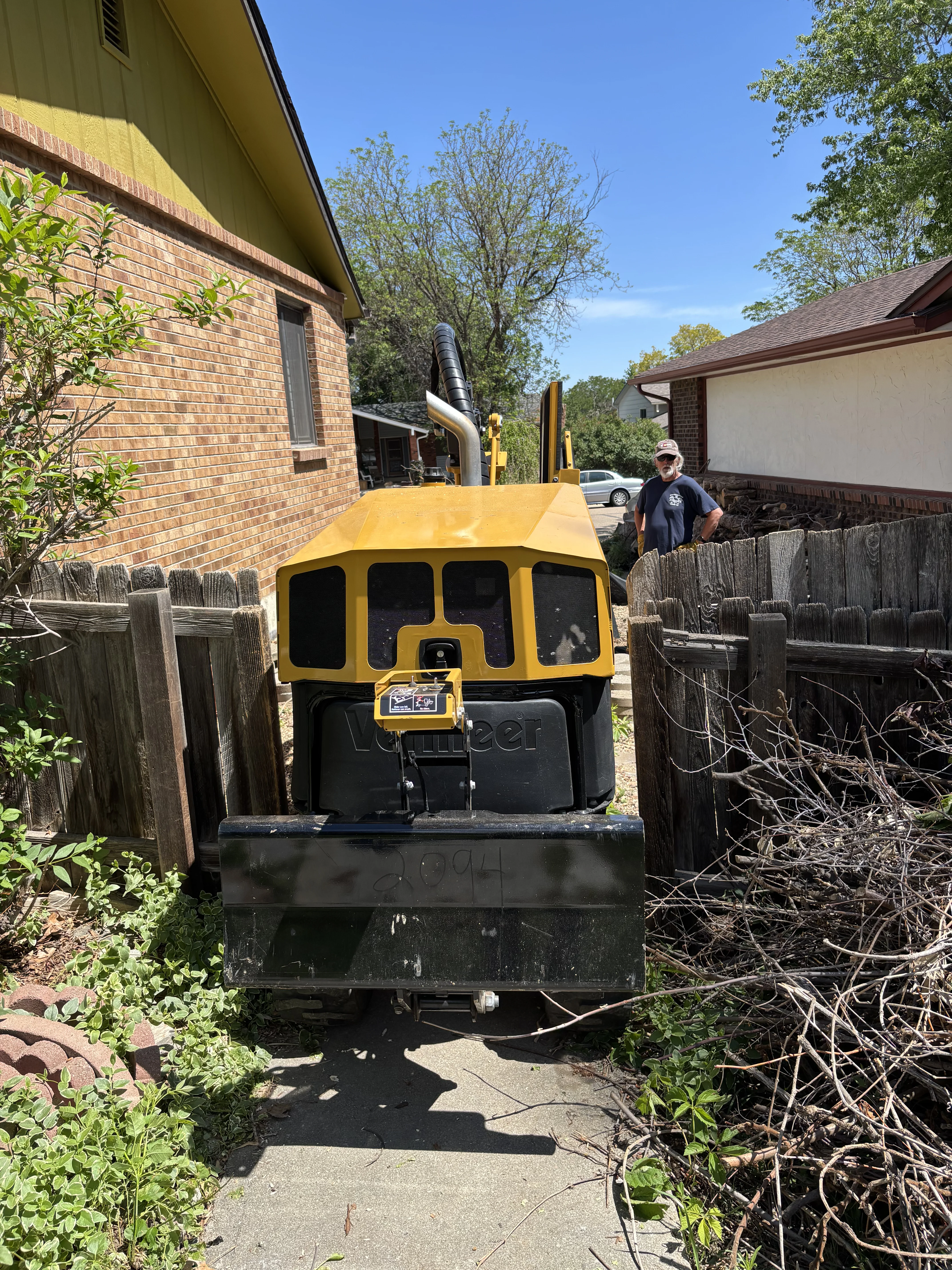 Compact stump grinder working in a narrow fenced backyard